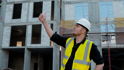A construction worker inspects the wall of a building on a construction site.