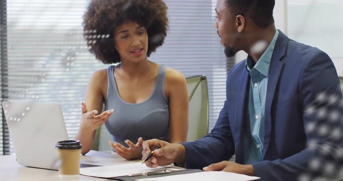 Woman reaching laptop, man leaning in, working over docs with animated map and code guiding review
