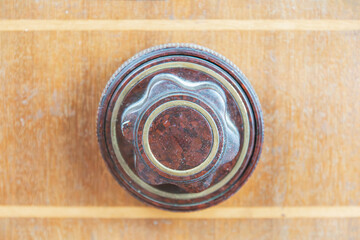 Close-up of vintage brass or bronze tube radio player, with intricate sunburst-like central ring and polished surface Set on wooden table, showing natural grain pattern Soft lighting, gentle shadow