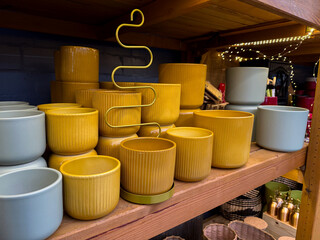 Different empty ceramic flower pots on wooden shelf at a gardening shop