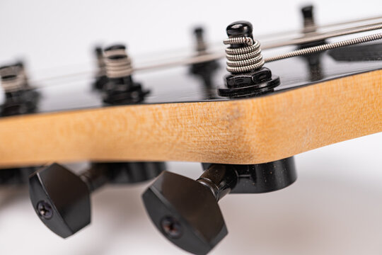 Close-up view of a modern heavy rock electric guitars headstock, showcasing its six symmetrical tuning pegs against a dark background with soft lighting