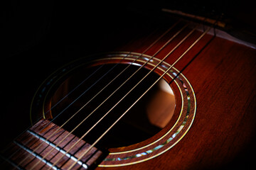 Obraz premium Close-up view of a brown acoustic guitar with steel strings and metal frets, showcasing wood texture and glossy finish The guitar is angled, emphasizing the neck curvature and string alignment Soft