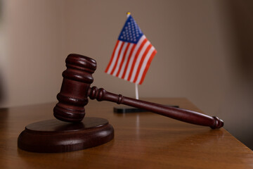 A wooden gavel and an American flag are sitting on a wooden table