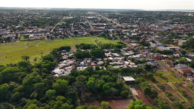 Left tracking aerial over Posadas, Argentina, specifically above Alberto Roth Botanical Garden with large trees and vegetation on a sunny day.