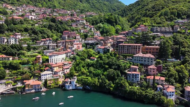 Nesso village showcasing traditional houses cascading down the hillside to Lake Como, surrounded by lush green mountains and reflecting Italian charm, drone establishing shot, Lombardy, Italy