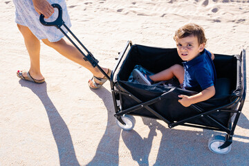 Child sitting in wagon being pulled along path.