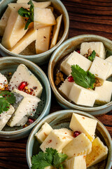 Close-up assortment of four hard cheeses in rustic bowls
