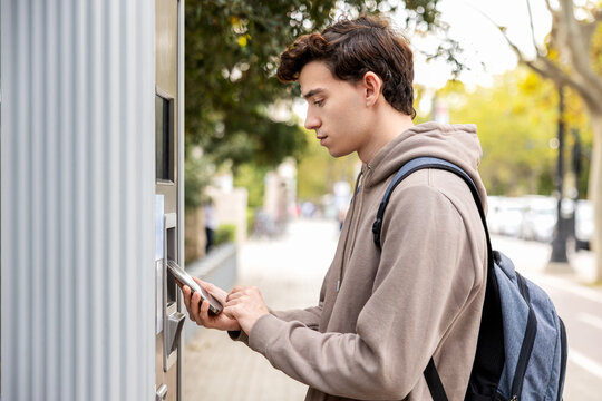 Student making a mobile payment at public touchscreen machine on city sidewalk