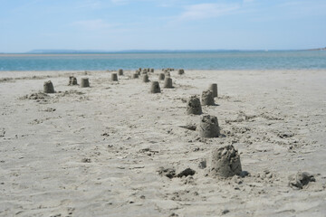 Rows of Small Sandcastles on a Wide Sandy Beach Leading to the Ocean