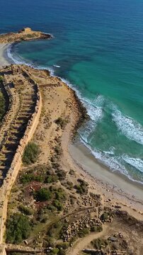 Aerial drone view of the coastal ruins of Leptis Magna, an ancient Roman city in Libya. Vertical