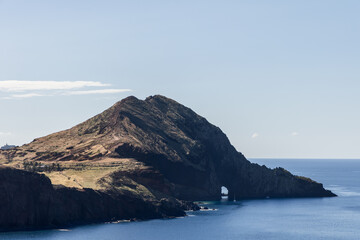 Close view of rocky headland at Sao Lourenco Point in Madeira, with its striking natural sea arch carved into mountain slope and calm blue Atlantic below