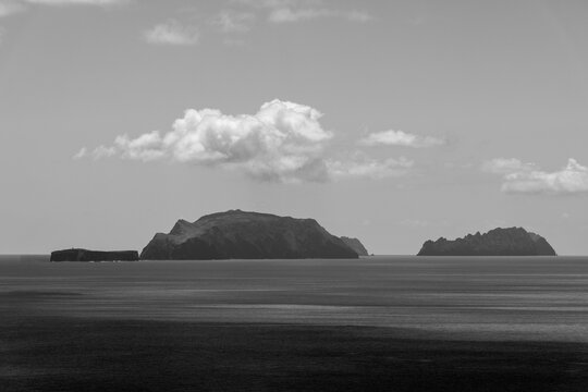 Monochrome view of the Desertas Islands Chao Deserta Grande and Bugio seen from Ponta de Sao Lourenco Madeira under soft clouds above calm Atlantic waters