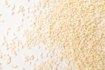 A close-up of white sesame seeds. Texture of healthy, calcium-rich sesame seeds. Scattered seeds on...