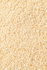 A close-up of white sesame seeds. Texture of healthy, calcium-rich sesame seeds. Scattered seeds on white background. Organic sesame, cooking ingredient, Asian seasoning