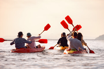 Group of young friends are kayaking together at calm sunset sea. Sea tropical resort vacations concept