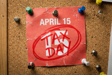 Red April 15 tax day reminder note pinned on corkboard