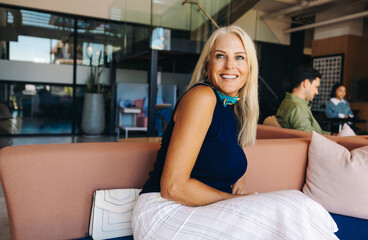 Smiling blonde woman sitting on a couch in a modern workspace