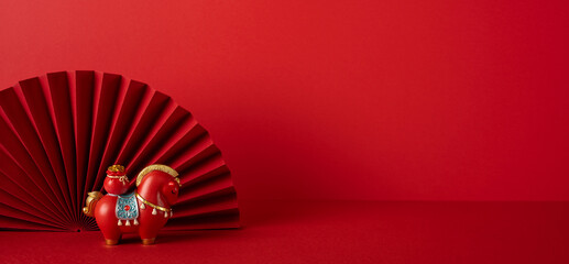 Side view of a festive red Chinese New Year display featuring a decorative fan and a toy horse, capturing celebration, luck, and tradition through vibrant color and cultural charm