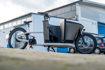 Electric Cargo Bike in Front of Industrial Building, Backlit Outdoor Urban Scene