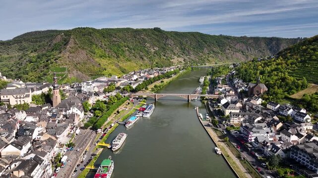 Aerial footage of historic town of Cochem with stone arch bridge Skagerrak Bridge, churches of St. Remaclus and St. Martin and Moselle River.