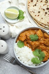 Delicious chicken tikka masala served on grey textured table, flat lay