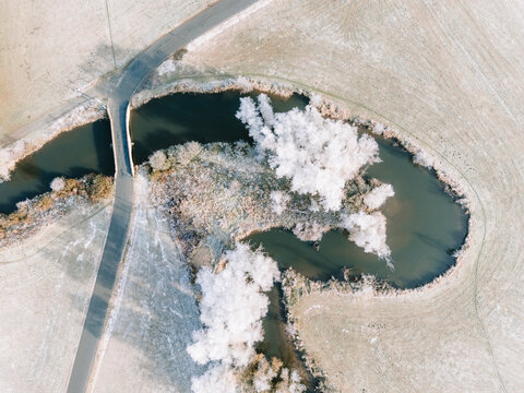 Luftaufnahmen einer winterlichen Flussauen-Landschaft bei Sonnenschein