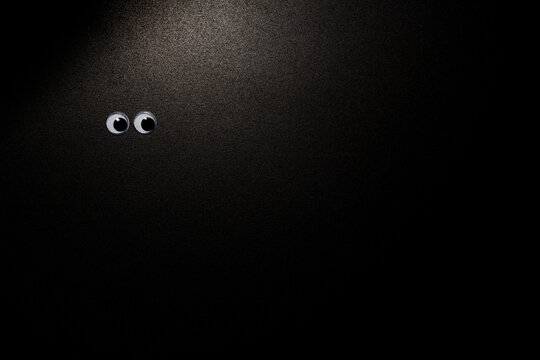 Black background with two eyes in the corner of the room. Close-up. Copy Space