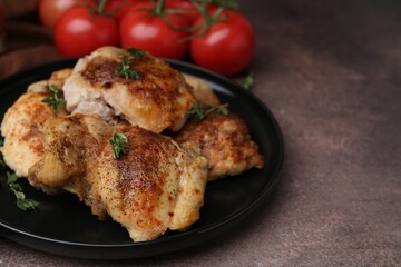 Tasty cooked chicken thighs with thyme and tomatoes on brown table, closeup. Space for text