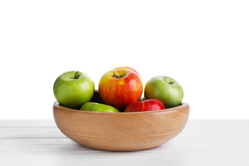 Red and green ripe apples in bowl on wooden table against white background