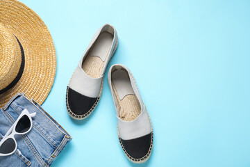 Stylish shoes, hat, jeans and sunglasses on light blue background, flat lay. Space for text
