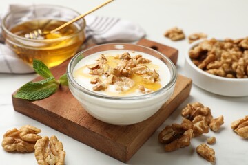 Delicious Greek yogurt with honey and walnuts served on white table, closeup