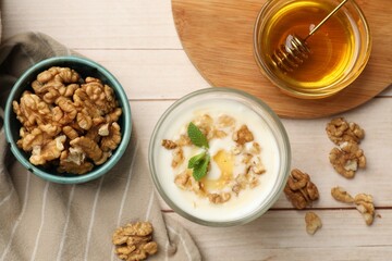 Delicious Greek yogurt with honey and walnuts served on white wooden table, flat lay