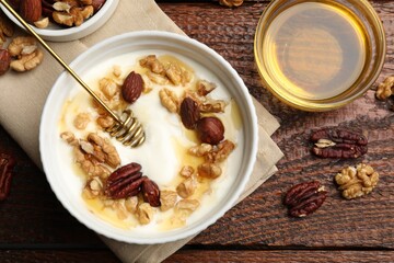 Delicious Greek yogurt with honey and nuts served on wooden table, flat lay