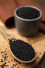 Aromatic black caraway in spoon and bowl on table, closeup