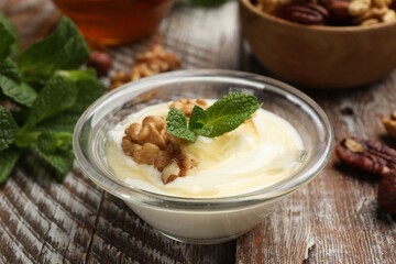 Delicious Greek yogurt with honey, nuts and mint on wooden table, closeup