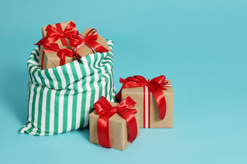 Santa Claus bag with Christmas gifts on light blue background, space for text