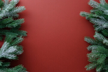 Christmas frame of pine branches on rich red background.