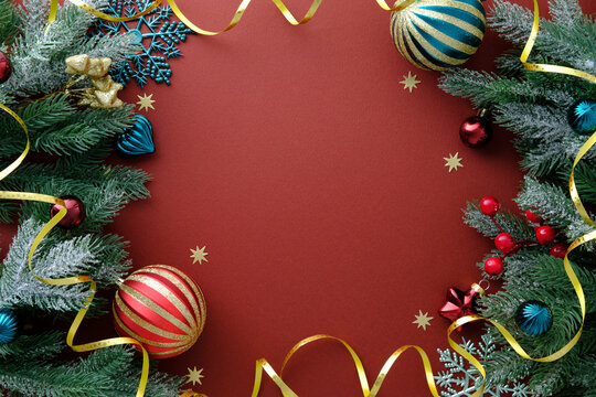 Christmas frame border made of pine branches, gold ribbons and bright red and turquoise ornaments