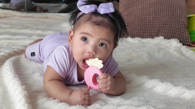 A baby lifting a teething toy and putting it into their mouth with curiosity