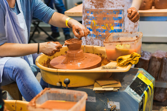 Close-up of hands adjusting and smoothing wet clay on a pottery wheel in a creative ceramic activity.