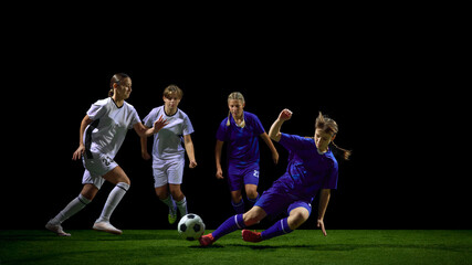 Young female soccer players sliding in intense tackle for ball. Concept of training analysis, coaching materials, aggressive play examples, sports education, youth development.