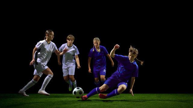Young female soccer players sliding in intense tackle for ball. Concept of training analysis, coaching materials, aggressive play examples, sports education, youth development. - Powered by Adobe