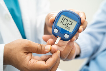 Doctor check diabetes from finger blood sugar level with finger lancet.