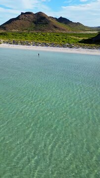 Aerial drone view of a person standing in shallow turquoise water at Balandra Beach , near La Paz, Mexico. Vertical