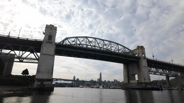 Gimbal wide booming down shot of the Burrard Bridge spanning False Creek on an autumn day in Vancouver, British Columbia, Canada. 4K