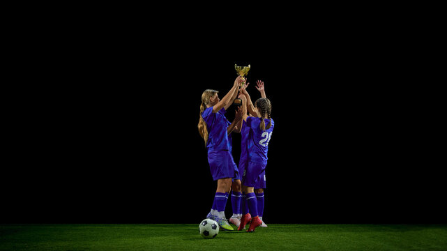 Teenage soccer team raising trophy together in victory moment. Concept of youth tournament wins, award promotions, sports achievement materials, motivational communication.
