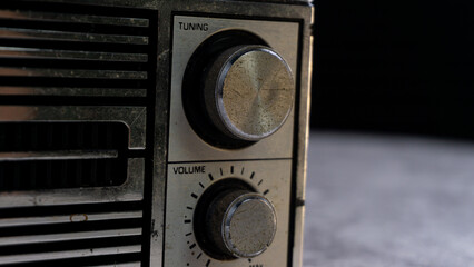 Detailed close-up of the tuning and volume knobs on an old radio, featuring worn metal and engraved markings. Great for showcasing analog devices and vintage industrial design.