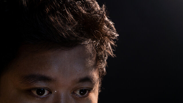 A dramatic close-up of a man?s eyes and forehead in low-key lighting, highlighting texture, emotion, and subtle expressions. Ideal for concepts of focus, tension, or deep thought. - Powered by Adobe