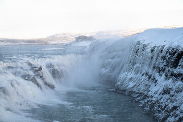 Winter Wasserfall über eisige Klippen in blauer isländischer Landschaft

