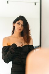 Woman in black off-shoulder dress standing indoors